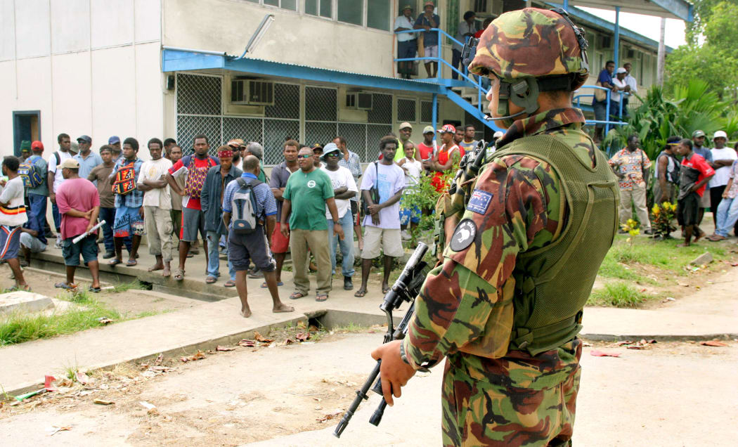 Locals look on as New Zealand soldiers and police guard the Honiara Magistrates Court in 2006, when opposition member of parliament Charles Dausabea appeared in court.