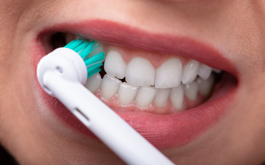 Close-up Of A Woman's Hand Brushing Teeth With Electric Toothbrush.