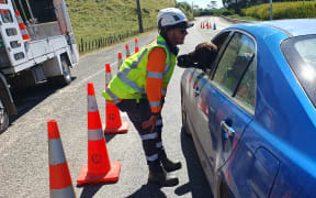 Liam Harvey checks with a driver, and dog, heading out past the 'closed except to residents' signs near the intersection of SH2 and SH5 on Wednesday.