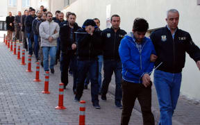 Turkish police officers escort people arrested in the central city of Kayseri for alleged links with Muslim cleric Fethullah Gulen.