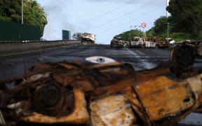 Burnt vehicles are seen on a road leading to the capital in Noumea.