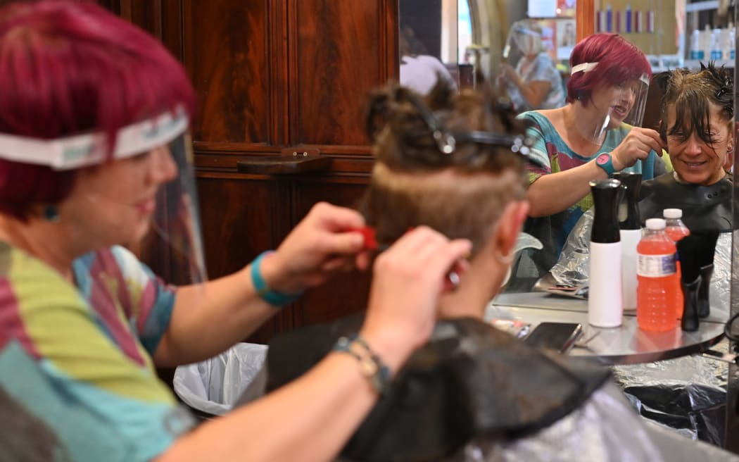 A hair stylist wears a PPE facemask as she works at a hair salon in Birkenhead, north west England on July 4, 2020. -