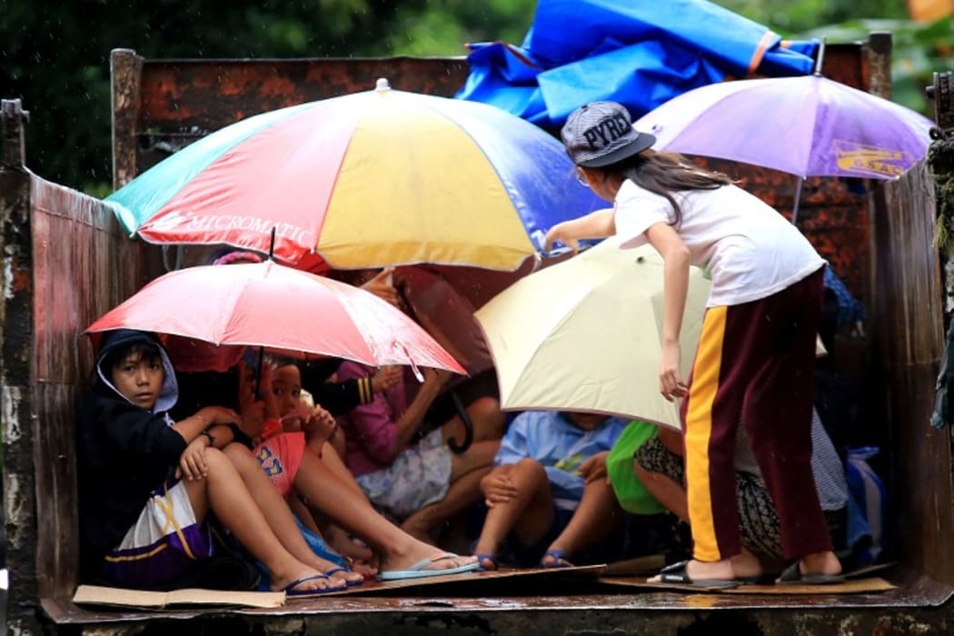Young Phillipines residents sit in a truck after the local government implemented preemptive evacuations at Barangay Matnog, Daraga, Albay province, due to the approaching typhoon Nock-Ten