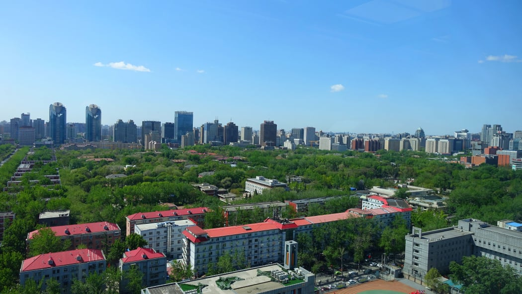 View of downtown Beijing taken from a tall building showing modern skyscrapers and parks with tall green trees