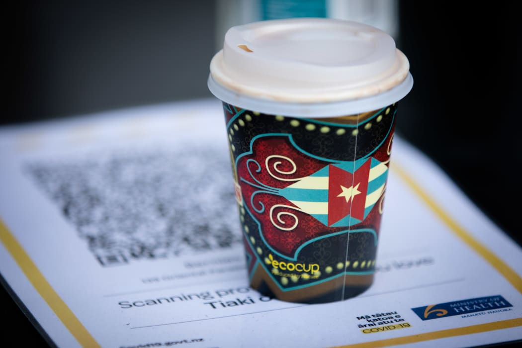 A takeaway coffee cup next to a QR code