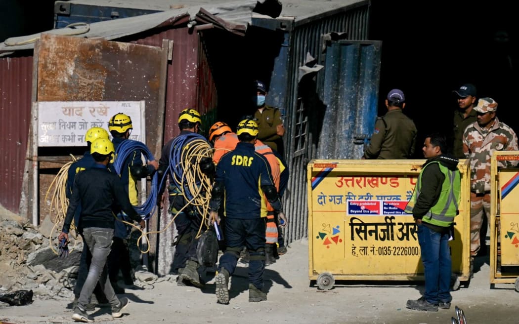 State Disaster Response Force (SDRF) personnel walk into the tunnel as rescue operation enters its final phase, to free workers trapped in the Silkyara under construction road tunnel, days after a portion of it collapsed in the Uttarkashi district of India's Uttarakhand state on November 23, 2023. Ambulances were on standby on November 23 morning, as Indian rescuers dug through the final metres of debris separating them from 41 workers trapped in a collapsed road tunnel for nearly two weeks. (Photo by Arun SANKAR / AFP)