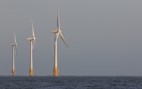 Offshore wind turbines. Wind farm on the sea horizon. Clean energy. Profile of three massive sustainable resource power generation turbines.