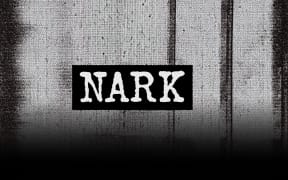 Black and white grainy image. Prison bars appear behind then, with the word 'Nark' in all caps in white with a black strip behind the words.