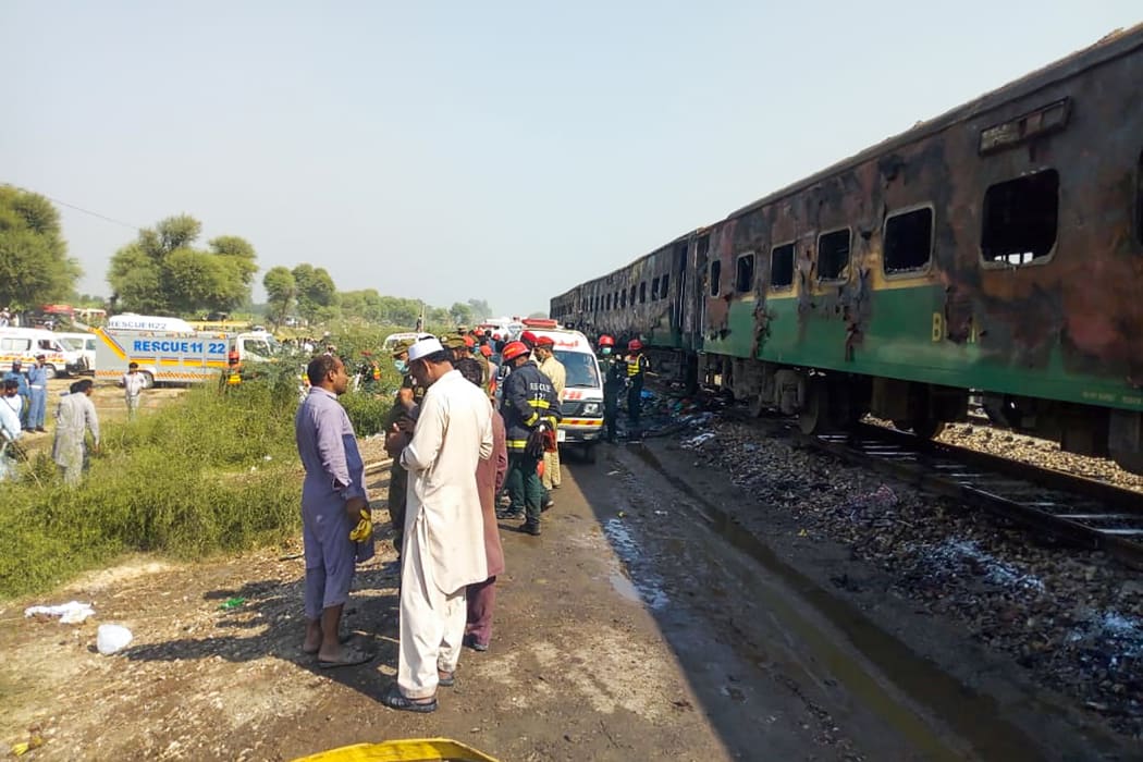 Rescue workers gather beside the burnt-out train carriages after a passenger train caught on fire near Rahim Yar Khan in Punjab province on 31 October, 2019.