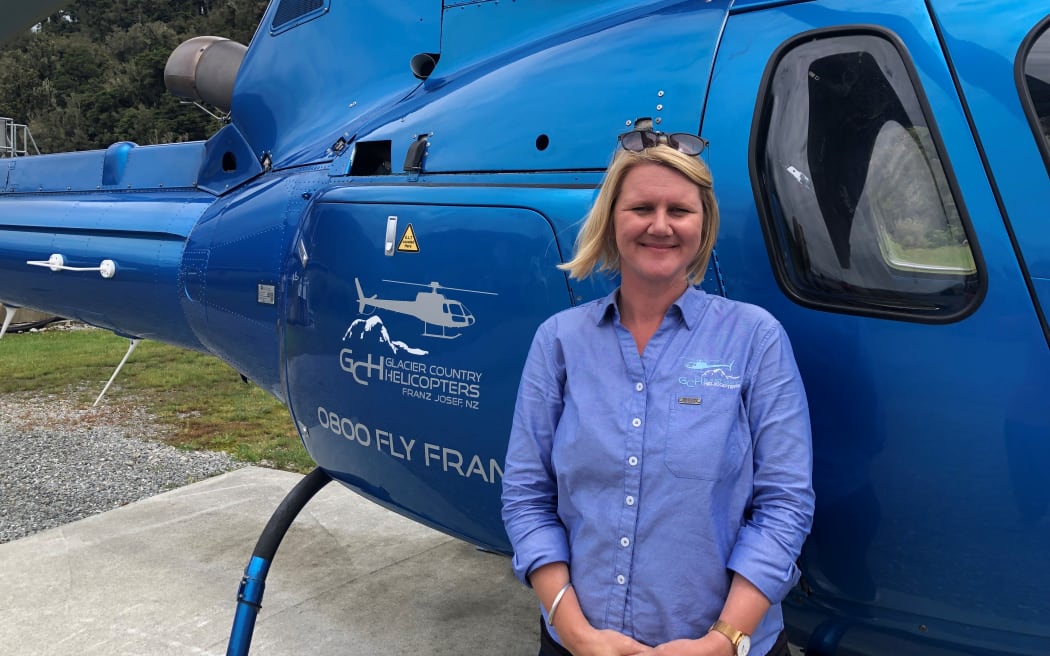 Women, Poppy Gordon, standing in front of a blue helicopter.