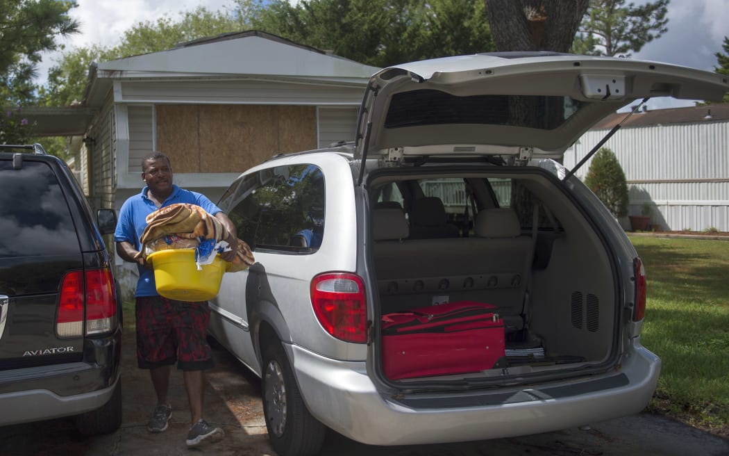 North Carolina resident Roberto Guzman carries belongings from his mobile home as he leaves Wilmington a day before the storm is due to strike.