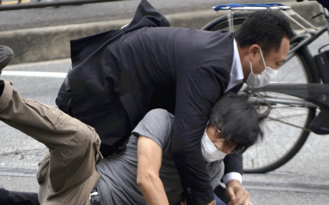 A man suspected of shooting Japanese Prime Minister Shinzo Abe at Yamato Saidaiji Station in Nara Prefecture on July 8, 2022 is wrestled to the ground.  67-year-old Abe has reportedly been shot in the chest during a stumping tour in Nara in the morning on July 8.