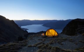 Illuminated tent by the lakeshore at dusk