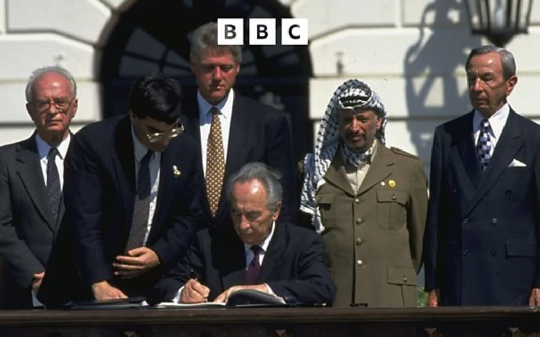 Israeli Foreign Minister Shimon Peres signs the historic Oslo Accords looked on by (from left) Israeli Prime Minister Yitzhak Rabin, unidentified aide, US President Bill Clinton and PLO Chairman Yasser Arafat.