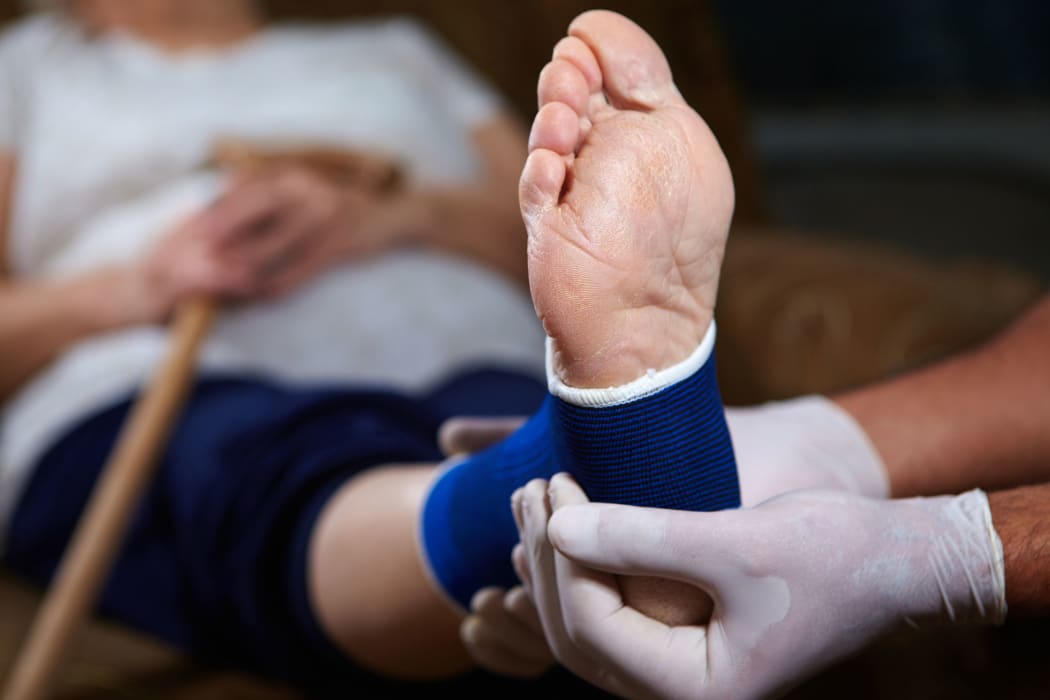A woman with a broken or sprained foot having her leg bandaged.