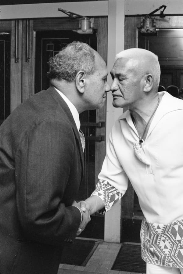 Two men touch noses with their eyes closed.