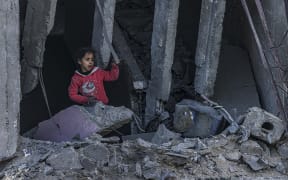 A Palestinian child stands amid the rubble of a building where two hostages were reportedly held before being rescued during an operation by Israeli security forces in Rafah, on the southern Gaza Strip on February 12, 2024.