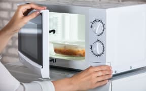 Woman's Hands Closing Microwave Oven Door And Preparing Food At Home
