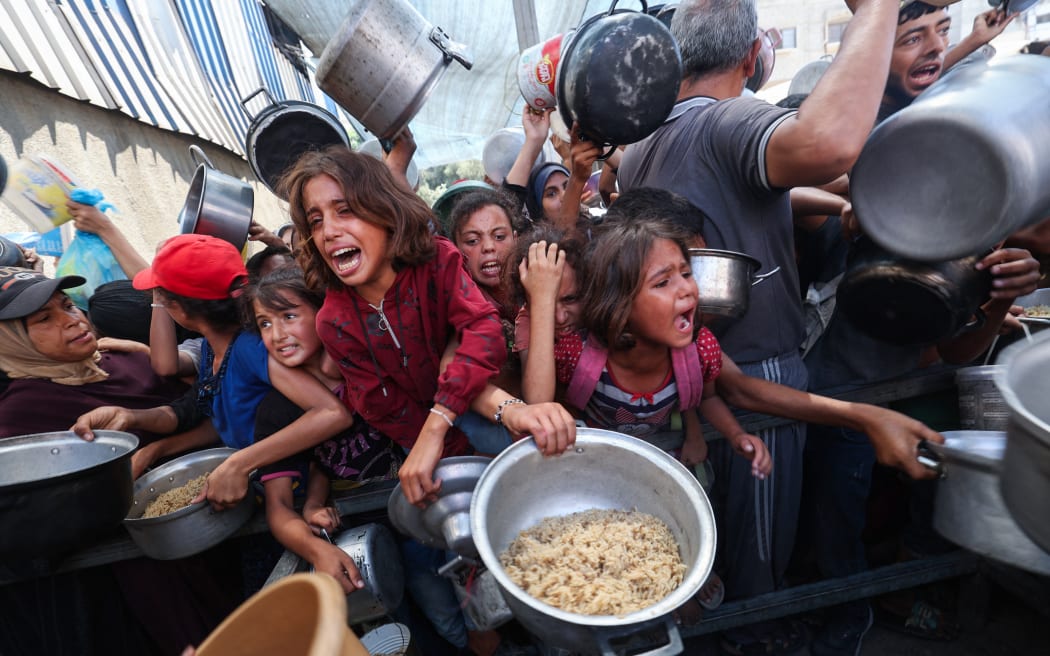 Palestinians shove to receive a hot meal from a charity kitchen in the Nuseirat refugee camp in the Israel-besieged Gaza Strip on September 4, 2025, where the UN has declared famine after nearly two years of war. (Photo by Eyad BABA / AFP)