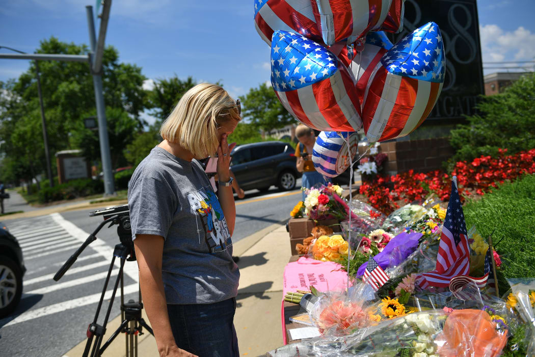 Christine Feldmann of Annapolis, who knew some of the shooting victims, stands before flowers, US flags and messages at a makeshift memorial.