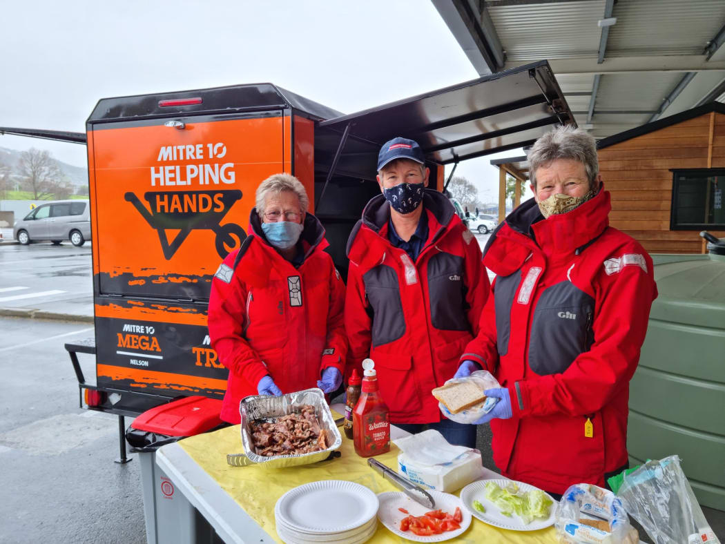 Coastguard volunteers cook bacon for sandwiches at the tradie vaccination and breakfast event.