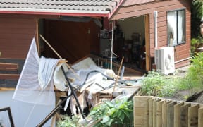Two homes were damaged after a car left Don Buck Road and drove down a bank, through the lounge of one property and ended up in the bedroom of a neighbouring one.