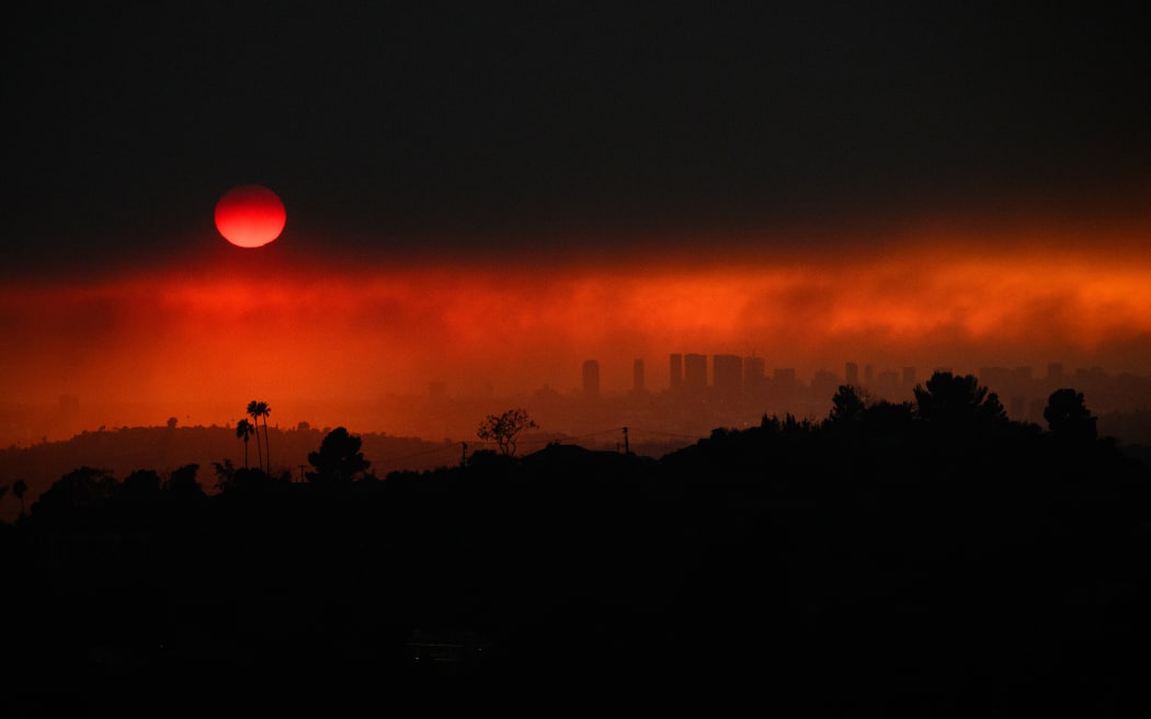 An aerial image shows smoke from wildfires including the Eaton Fire and Palisades Fire in Los Angeles, California, on January 8, 2025. - At least five people have been killed in wildfires rampaging around Los Angeles, officials said on January 8, with firefighters overwhelmed by the speed and ferocity of multiple blazes. (Photo by Patrick T. Fallon / AFP)