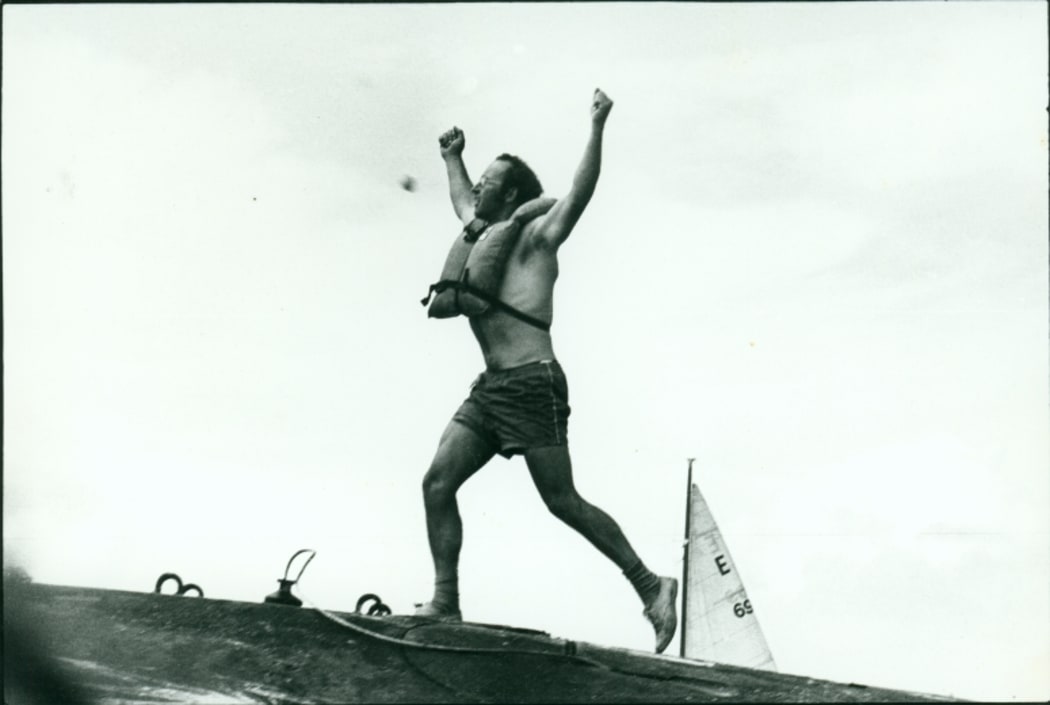 n image of Stephen Sherie on the hull of the USS Haddo, arms raised aloft.