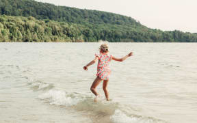 Child playing in water on beach.