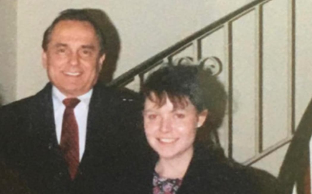 An image of a young Rachel Lees standing beside Bill Gothard in front of a staircase.