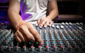 Sound engineer hand adjusting eq knobs on audio mixing console. recording and broadcasting concept.