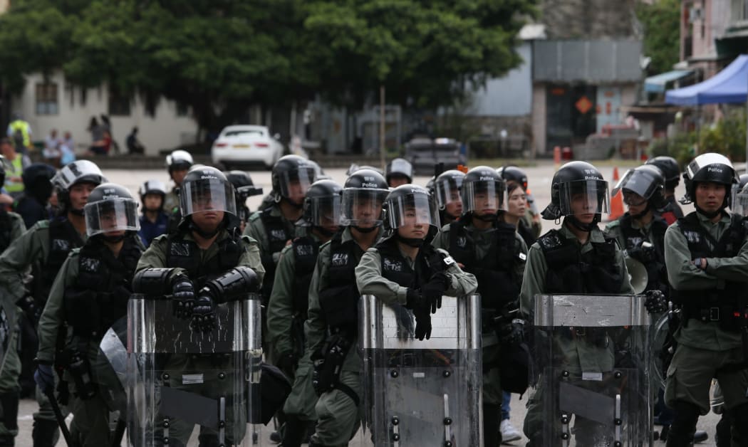 Riot police block the entrance of the Nam Pin Wai village in Yuen Long, Hong Kong, on Saturday July 27, 2019 as protesters gather outside the village