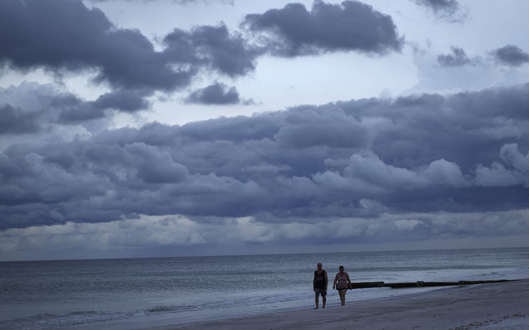 TREASURE ISLAND, FLORIDA - SEPTEMBER 27: People walk the beach at sunset in advance of the arrival of Hurricane Ian on September 27, 2022 in Treasure Island, Florida. Ian is expected in the Tampa Bay area Wednesday night into early Thursday morning.   Win McNamee/Getty Images/AFP (Photo by WIN MCNAMEE / GETTY IMAGES NORTH AMERICA / Getty Images via AFP)