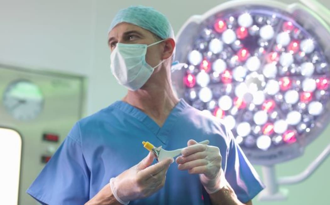 Orthopaedic surgeon in operating theatre with replacement hip stem (file)