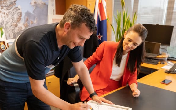 David Seymour and Jacinda Ardern with the signed transcript of her calling him an "arrogant prick" in Parliament. They plan to auction it off to charity.