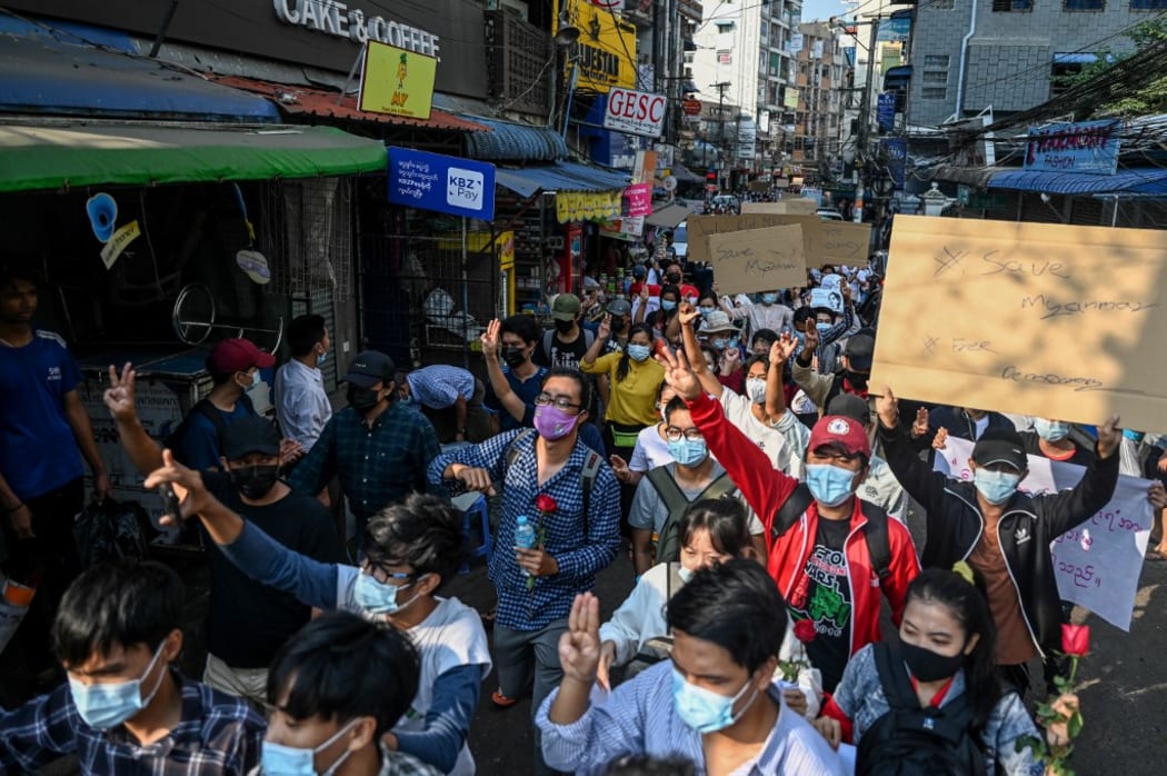 Protesters hold up the three finger salute and banners as they march through a market area during a demonstration against the military coup in Yangon on February 7, 2021.