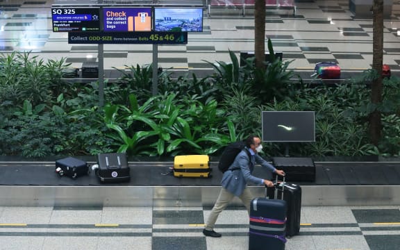 A man wearing a mask collects his bag after arriving in Singapore on the first 'vaccinated lane' flight from Germany on 8 September.
