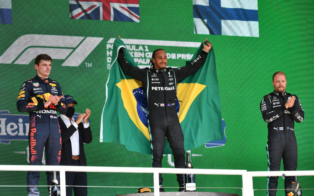Mercedes' British driver Lewis Hamilton (C), Red Bull's Dutch driver Max Verstappen (L) and Mercedes' Finnish driver Valtteri Bottas celebrate on the podium after obtaining the first, second and third positions respectively, in Brazil's Formula One Sao Paulo Grand Prix on November 14, 2021.