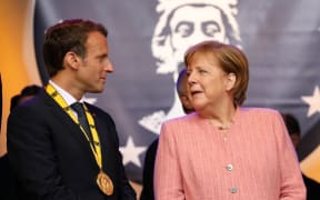 France's President Emmanuel Macron stands next to German Chancellor Angela Merkel at the end of the Charlemagne prize award ceremony on May 10, 2018 in Aachen, western Germany.
