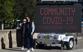 People walk past a sign for a Covid-19 testing clinic at Bondi Beach in Sydney 27 June, 2021.