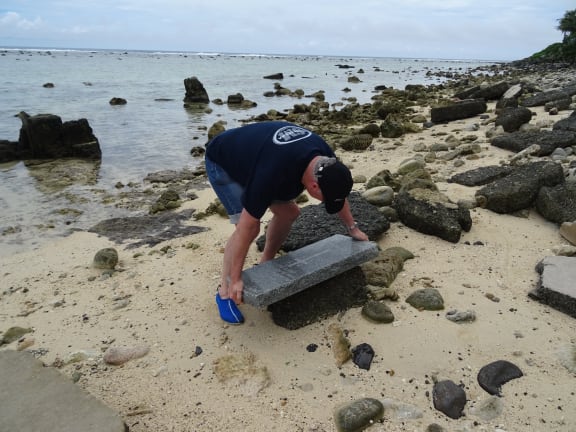 Cate Walker's husband Paul tries to life the headstone of a Cook Island veteran of the First World War on Rarotonga.