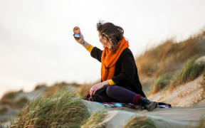 Woman looking at compact mirror on beach (Photo by Tom Dunkley / Connect Images / Connect Images via AFP)