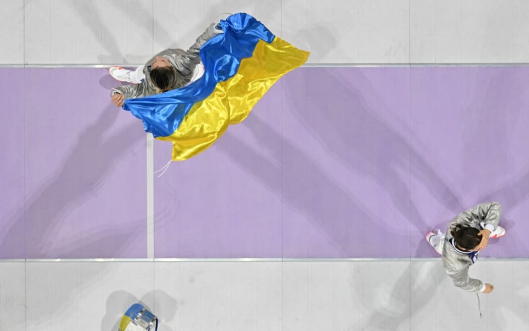 An overview shows Ukraine's Olga Kharlan celebrating after winning in the women's sabre team gold medal bout between South Korea and Ukraine during the Paris 2024 Olympic Games at the Grand Palais in Paris, on August 3, 2024. (Photo by Fabrice COFFRINI / AFP)