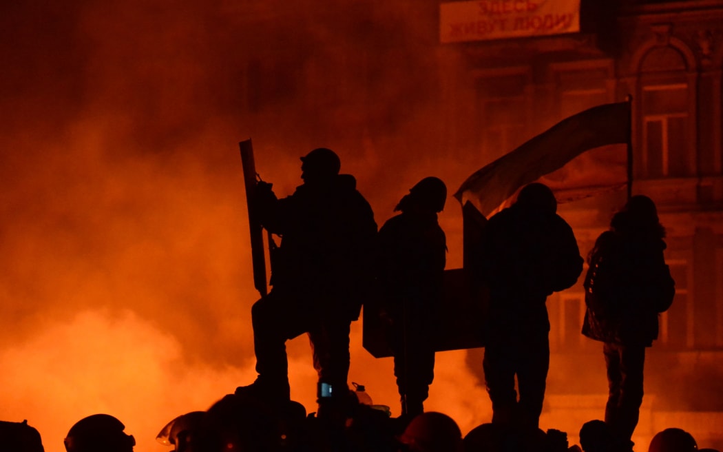 Ukrainian anti-government protesters stand on a makeshift barricade during clashes with riot police in Kiev.