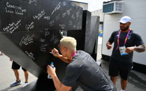 Athletes sign the NZ pou at the 2018 Commonwealth Games village