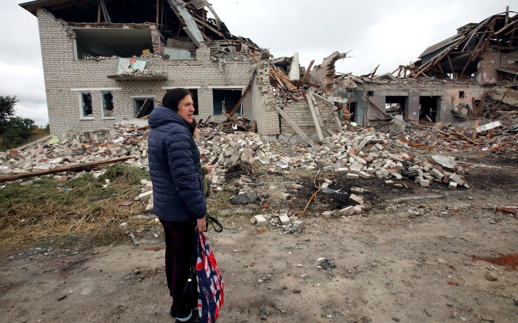 A woman stands near a lyceum destroyed as a result of shelling in Verbivka village, Balakliia community, in Kharkiv Region, northeastern Ukraine on 13 September, 2022.