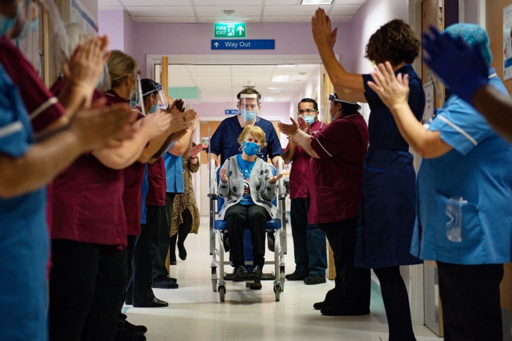 Margaret Keenan (C), 90, is applauded by staff as she returns to her ward after becoming the first person to receive the Pfizer-BioNtech Covid-19 vaccine at University Hospital in Coventry, central England, on December 8, 2020.