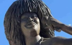 A bronze sculpture of Tina Turner smiling and holding a microphone.