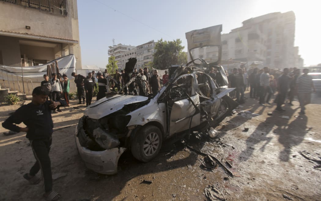 Palestinian people gather around and look inside a destroyed vehicle targeted by the Israeli military in Gaza City in the Gaza Strip on November 22, 2025. According to Gaza's Civil Defence Agency, seven individuals were killed in three Israeli airstrikes on Palestinian territory that day. A spokesperson for the agency, which operates under Hamas authority, said three people were killed in the attack on the vehicle. Three others died in an assault on a home in Deir al-Balah, and one person was killed in a third strike in the Nuseirat area. (Photo by Hashem Zimmo / Middle East Images via AFP)
