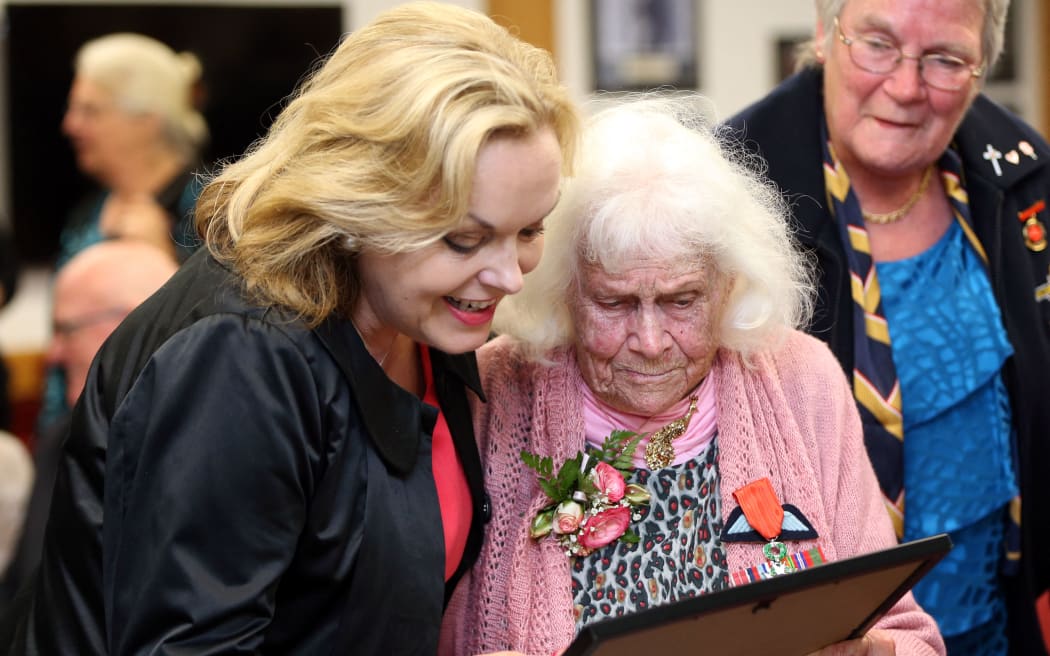 New Zealand's member of parliament Judith Collins (left) and Phyllis Latour Doyle look at the Knight of the national Order of the Legion of Honour award she received from French Ambassador to New Zealand Laurent Contini in Auckland on November 25, 2014.